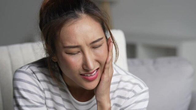 Young Asian woman suffering from toothache.