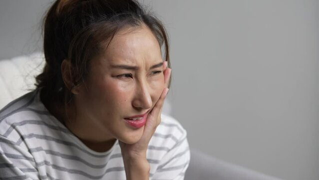 Young Asian woman suffering from toothache.