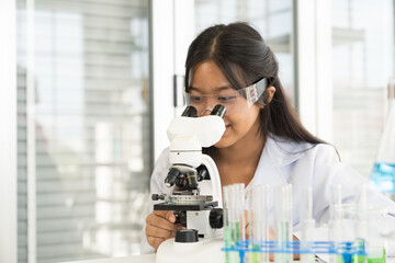 Asian child girl scientists learning science and doing analysis for germs and bacteria with microscope in the laboratory. Science and education, researcher and discovery concept