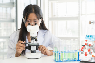 Asian child girl scientists learning science and doing analysis for germs and bacteria with microscope in the laboratory. Science and education, researcher and discovery concept
