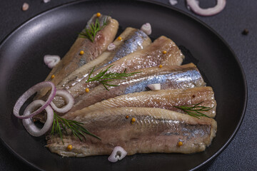 Fillet of pickled marinated sea herring fish with shallots and dill. Served ready to eat seafood