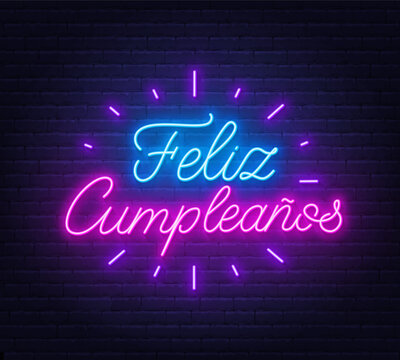 Feliz Cumpleanos neon lettering on brick wall background.