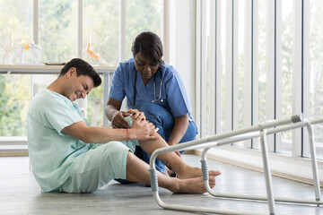 Obraz premium Female nurse caring male patient falling from walker to the floor in patient room at hospital. Accident and Health care concept