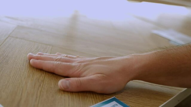 Man touching wood texture of laminate floor sample in flooring shop.
