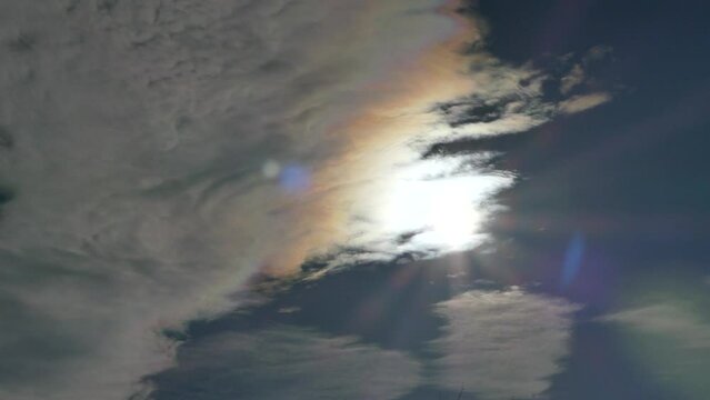 Blue sky and clouds Iridescence, Irisation around sun - colorful optical phenomenon at high level of clouds in real time. Topics: weather, meteorology, optical phenomenon, natural colors