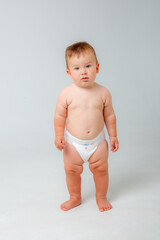 Smiling happy baby . Portrait of a little toddler boy, a baby in a diaper stands and laughs in...