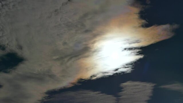 Blue sky, flying birds and clouds Iridescence, Irisation around sun - colorful optical phenomenon at high level of clouds in real time. Topics: weather, meteorology, optical phenomenon, natural colors