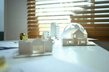 Architectural model of houses on desk with drawing tools and blueprints. Building, construction and architect concept