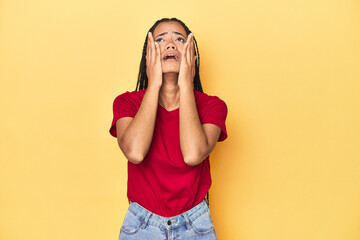 Young Indonesian woman on yellow studio backdrop whining and crying disconsolately.