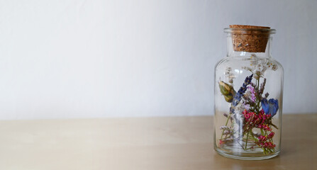 Bottle with dry flowers or medicinal herbs, and a cork.