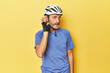 Cyclist wearing helmet in yellow studio trying to listening a gossip.