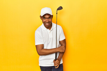 African American man golfer, yellow studio backdrop, laughing and having fun.
