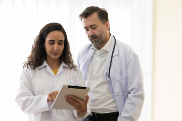 Fototapeta premium Male and female doctor discussing of work on digital tablet at hospital