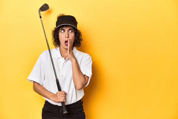Athletic Caucasian woman with curly hair golfing in studio is saying a secret hot braking news and looking aside