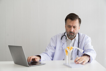 Senior male doctor wear uniform with stethoscope working with laptop computer and research of model...