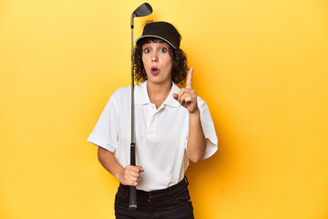 Athletic Caucasian woman with curly hair golfing in studio having an idea, inspiration concept.