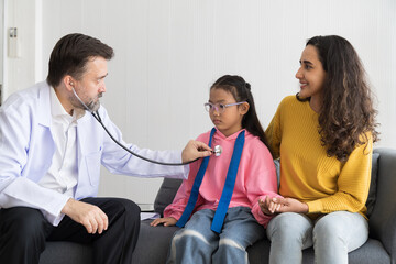 Obraz premium Senior male doctor examining kid child girl by stethoscope at hospital