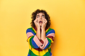 Curly-haired woman in multicolor sweatshirt whining and crying disconsolately.