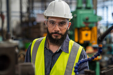 The technician is working in a steel factory. The Industrial engineer wearing protective clothing puts on hard hat.