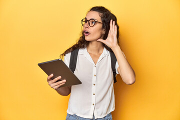 Student holding a tablet, glasses, backpack on, trying to listening a gossip.