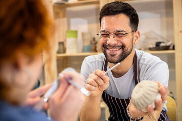 Man working in pottery studio workshop making bowl from clay.