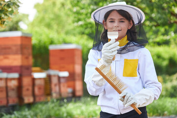Portrait of smiling girl holding hive fork and brush