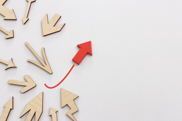 Arrows on a white paper background, with one of them painted red bursting forward. Idea of...