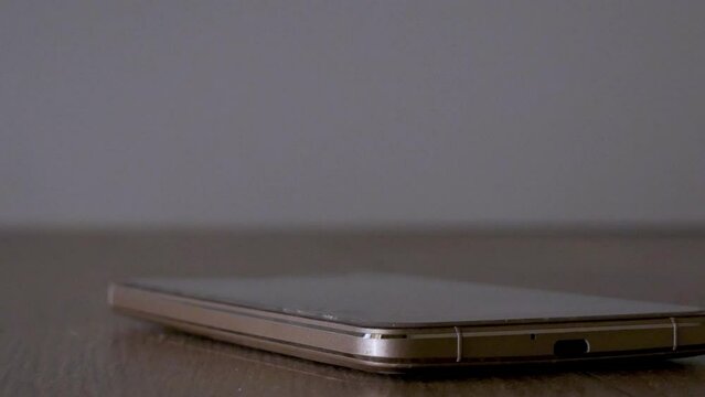 close up teps on a smartphone to destroy the phone illuminated by police lights