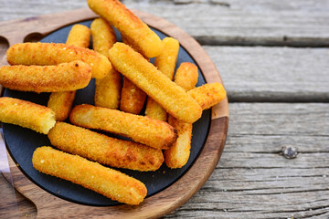 Vegetarian italian cheese breaded  oven baked  mozzarella sticks with  fresh basil on wooden background.Italian street food.
