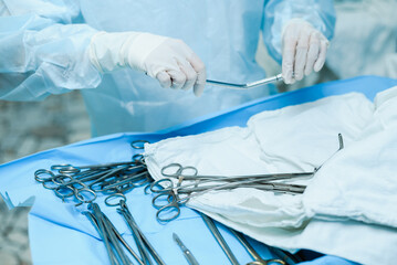 A nurse prepares medical instruments for surgery for surgeons