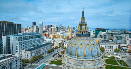 Aerial view of blue and gold gilded city hall dome with distant San Francisco skyscrapers