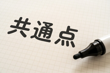 共通点と書かれたノートとマーカー