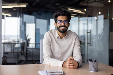 Portrait of a young Indian designer, engineer. of an architect sitting in the office at the desk...