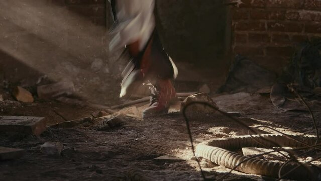 Wide shot of legs of psycho in clown costume chasing his victim in dusty abandoned place