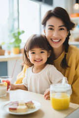 Little girl and mother happily having breakfast in the kitchen
