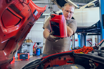 A Man with glasses Maintains a Car in a Garage