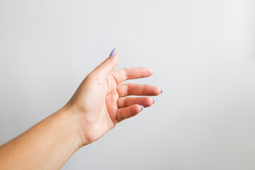 The woman's hand reaches out to catch or take and grasp something. Female hand on a white background