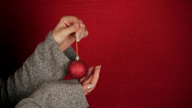 A red Christmas ball is like a symbol of the new year and Christmas. Female hands hold a Christmas tree toy. The girl gives a festive mood. New Year symbol of the dragon. Festive atmosphere.