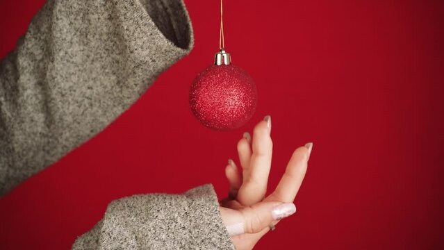 A red Christmas ball is like a symbol of the new year and Christmas. Female hands hold a Christmas tree toy. The girl gives a festive mood. New Year symbol of the dragon. Festive atmosphere.