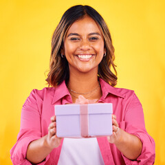 Happy woman, portrait and gift box for present, birthday or event against a yellow studio background. Female person smile giving prize, giveaway or celebration for surprise, package or ribbon parcel