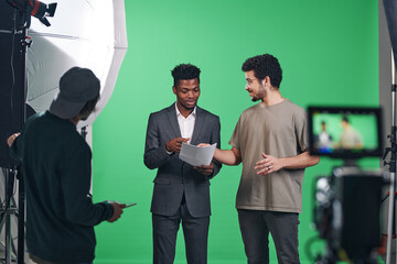 African American presenter discussing script with director while they standing in professional studio