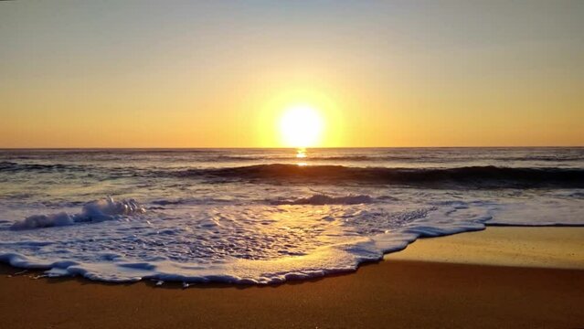 wunderschöner goldener Sonnenuntergang am Meer mit in Zeitlupe auslaufenden Wellen, Horizont, Brandung