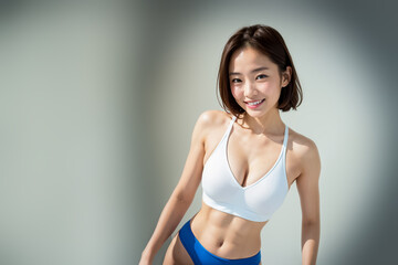 An adorable Asian sportswoman, sporting a sports bra and supportive underwear, stands isolated in front of a background. Generative AI. - obrazy, fototapety, plakaty