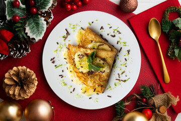 Crepe filled with pieces of banana marinated in lime juice on a table with Christmas decoration elements.