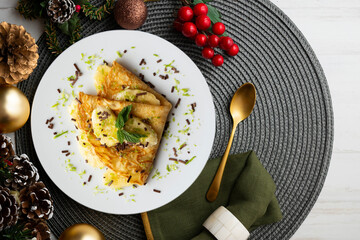 Crepe filled with pieces of banana marinated in lime juice on a table with Christmas decoration elements.
