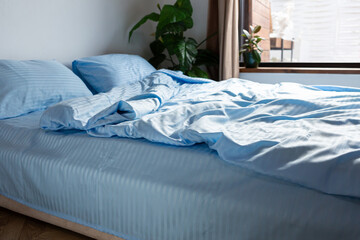 Close up of blue stripe satin bedding clothes on bed