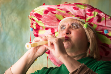 Clown in a hat. The buffoon grimaces and entertains. Portrait of a dressed up artist.