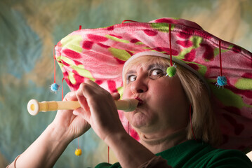 Clown in a hat. The buffoon grimaces and entertains. Portrait of a dressed up artist.