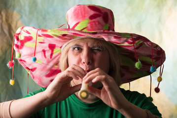 Clown in a hat. The buffoon grimaces and entertains. Portrait of a dressed up artist.