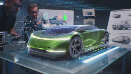 Two male automotive designers create design of eco-friendly electric car, choose color using tablet computer and futuristic augmented reality hologram. 3D graphics of vehicle developing. VFX animation